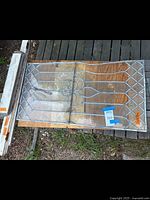 Full view of vintage leaded glass window showing fleur-de-lis pattern and diamond patterned panes laid flat on wooden deck outdoors