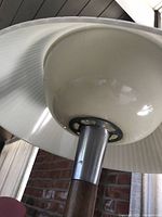 Underside of off-white pleated metal shade showing attachment hardware to stem