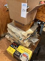 Stack of approximately 50 sheets of 12x12 inch glass mosaic tiles wrapped in protective paper with boxes on top including vintage copper enameling kit box