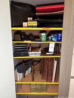 Shelf with vintage HP 35 calculator, wooden and plastic desktop organizers, stationery items including ink boxes, stapler, pencils, and various folders/envelopes.