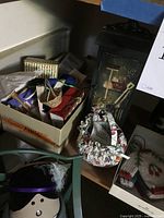 Photo of a collection of small items including dolls, miniatures, textile crafts, and a metal chair.