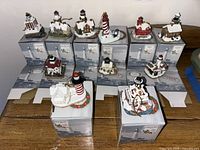 11 Harbor Lights lighthouse ornaments shown placed on boxes