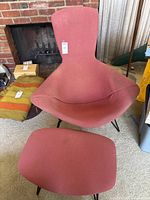Front view of red upholstered wire frame chair paired with matching ottoman