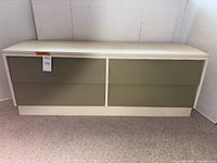 Front view of mid-century modern dresser with four green drawer fronts and off-white body.