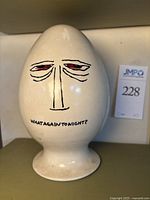 Front view of off-white egg container with stylized face and text