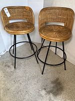 Front view of pair of wicker stools with metal bases