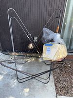 Three metal frames in folded butterfly chair shape with plastic bag of canvas covers
