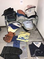 Photo of assorted hats, folded shirts, and gloves, displaying variety of motor sports themed apparel including branded hats and gloves.