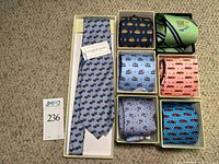 Overview of all seven silk ties in their original boxes arranged on beige carpet
