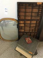 Antique oval convex mirror with light wooden frame, wooden printer's drawer leaning against the wall, and two vintage microscope slide storage boxes on carpeted floor.