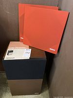 Photo showing one Pioneer CS-R3000 speaker with black and brown cabinet, accompanied by dark orange cloth covers and the instruction manual.