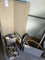 Overview shot of quilting and sewing supplies including two plastic containers filled with various small items, some quilting rulers, and several craft books against a pegboard background.