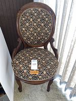 Front view of Victorian parlor chair showing needlepoint upholstery and wooden frame