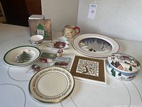 Full view of assorted vintage Christmas decor items on display including plates, mug, tin, ornaments, and holiday dishware. Shows condition and scale of the items in the lot.