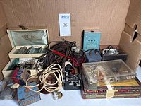 Overview of vintage cigar box, jewelry box with tubes and electronic parts, spools of wire, switches, and fuse boxes.