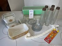 Wide view of all items including Pyrex baking dishes, clear bowls, Tupperware, glass bottles, glass jar, and cleaning wand