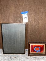 Both art pieces displayed side by side against wood background with lot tag