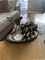 Image showing the set on a wooden coffee table including the silver tray, six goblets, and the silver and glass decanter holder with decanter inside.