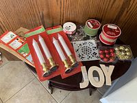 Photo of assorted Christmas crafting supplies including candles, ribbons, stencil sheets, bells, ornaments, and wooden letters