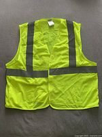 Front view of neon yellow perforated mesh safety vest with two vertical and one horizontal reflective grey stripes, laid flat to show full vest design and closure.