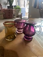 Three colorful decorative glass pieces set on table in living room environment