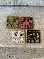 Four square wine coasters arranged in 2x2 on stone surface, showing all humorous text designs