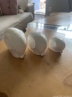 Front view of the three white elephant figurines, arranged largest to smallest on a wood surface.