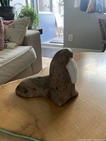 Photo of carved stone walrus figurine on wooden table in living room setting showing full length