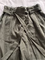 Close view of the olive green paperbag waist and the tied belt on the pants.