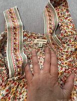 Close-up of Max Studio label and floral print with decorative vertical trim on shoulder straps.