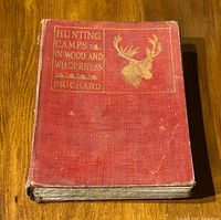 Front cover of the red hardcover book showing title 'Hunting Camps in Wood and Wilderness' by Prichard with gilt embossed moose head.