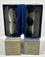 Two blue cardboard boxes filled with stacked Keystone stereoview cards shown standing upright with card images visible along the edges highlighting the quantity.