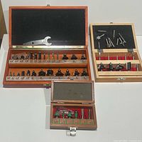 Overall photo showing three wooden cases containing various router bits, keyed for woodworking tool use.