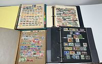 Four open stamp binders displaying various pages filled with stamps from different countries and regions.