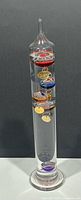 Front view of Galileo thermometer showing the colorful hanging spheres and internal liquid