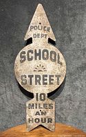Full image of hand-painted metal sign with text: POLICE DEPT, SCHOOL STREET, 10 MILES AN HOUR. Shows entire sign shape and surface wear.