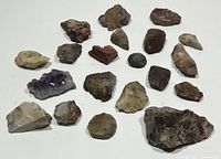 Wide view showing all stones included in the lot, placed on a white surface, showing variety in size, color, and texture.