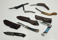 Overview of the entire collection showing 8 vintage box cutters and folding knives with various handle materials and a couple leather sheaths.