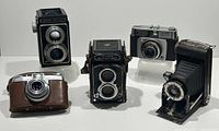 Front view of all five vintage cameras showing various forms including twin-lens reflex and folding cameras.