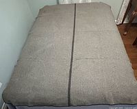 Grey wool blanket with central black stripe spread on bed, showing full size and condition.