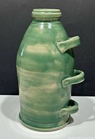 Green glazed ceramic jug with three handles, front view