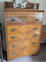 Front view of dresser showing five drawers, decorative inlay and brass hardware