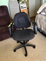 Front view of black office swivel chair showing fabric seat, mesh back, armrests, and caster wheels.