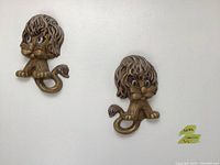 Two golden cat wall decor pieces displayed on a white background, showing overall size and look.