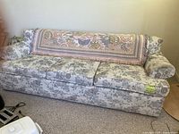 Full view of the traditional floral fabric couch with tapestry throw draped over the back.