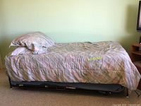 Twin trundle bed frame assembled with mattress covered in light-colored bedding and pillow on top.