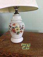 Close-up of the white ceramic lamp base with colorful floral design and the metal lamp holder.