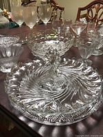 Overview of vintage glassware collection including a swan centerpiece on a large round serving plate and other decorative glass bowls and glasses.