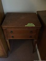 Wooden sewing machine desk closed with two drawers and some wear marks visible on top surface