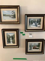 Four framed oil paintings on canvas showing different landscape scenes including river, snow-covered path, trees, and cabin, all signed Anneka.